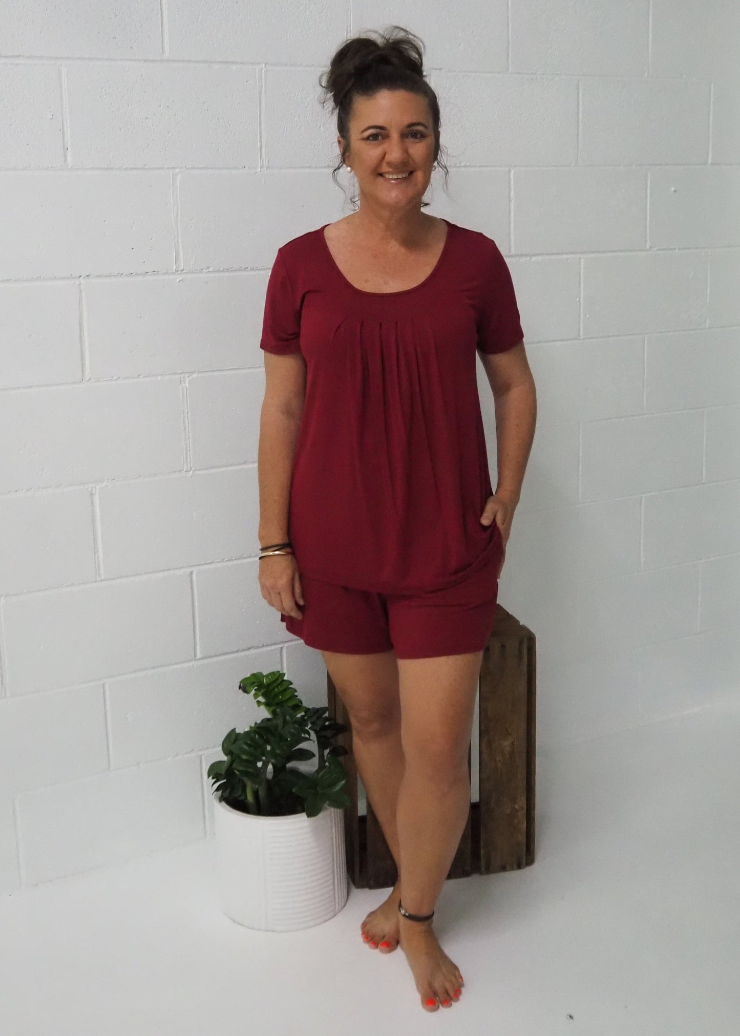 Model standing full-length in red bamboo short set with flowy top and elastic waist shorts