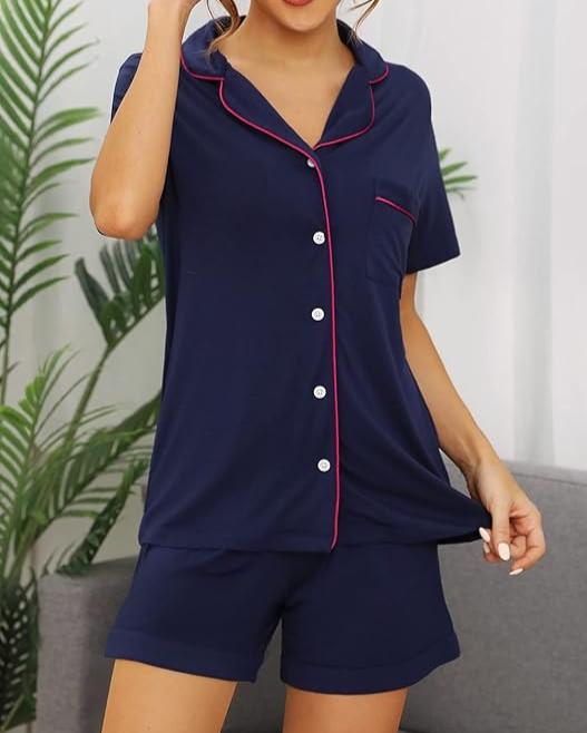 Woman wearing navy bamboo short pyjama set with red piping, button-up top and shorts, standing in a relaxed pose.