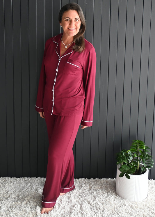 Model wearing Juliette deep berry long sleeve bamboo PJ set with white piping, button-up top and full-length pants, soft breathable thermoregulating sleepwear.